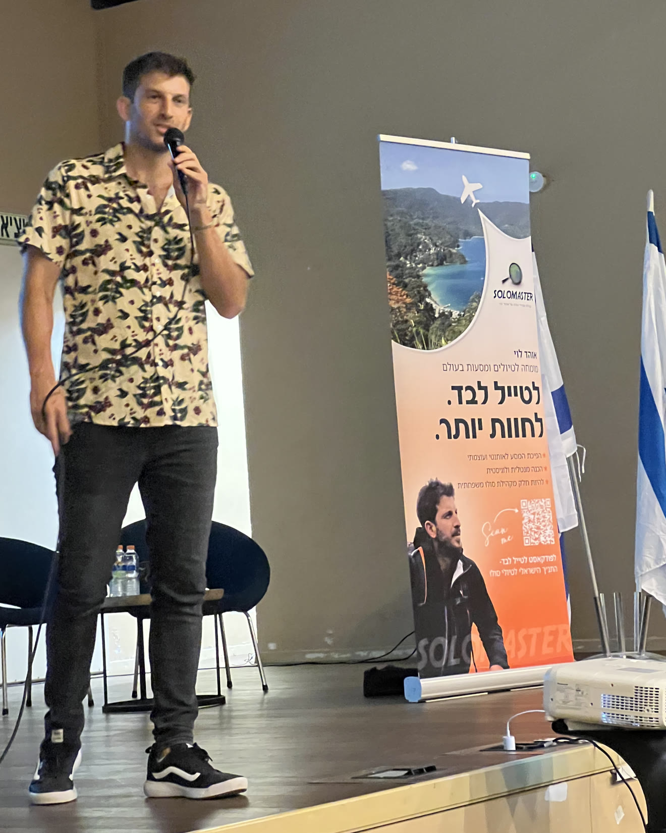 אוהד לוי על הבמה עם מיקרופון לצד באנר סולומאסטר